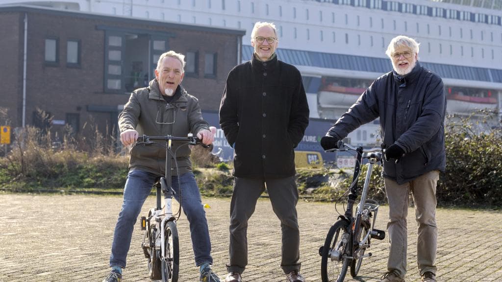 Drie mannen poseren met twee fietsen.