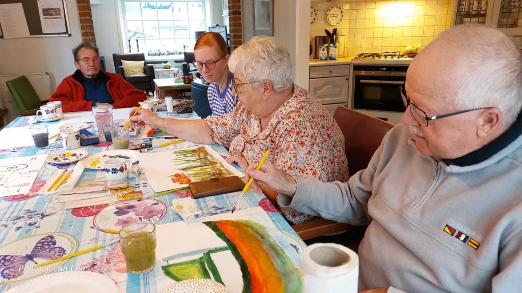 Ouderen die aan een tafel zitten te schilderen. 
