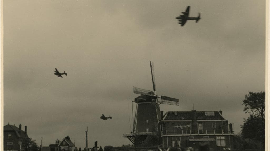 Drie bommenwerpers vliegen over een molen bij Terbregge om voedsel te droppen