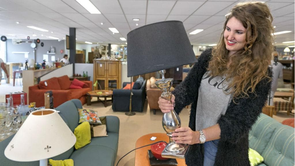 Iemand houdt een tweedehands lamp vast in een kringloopwinkel. Foto: gemeente Rotterdam.