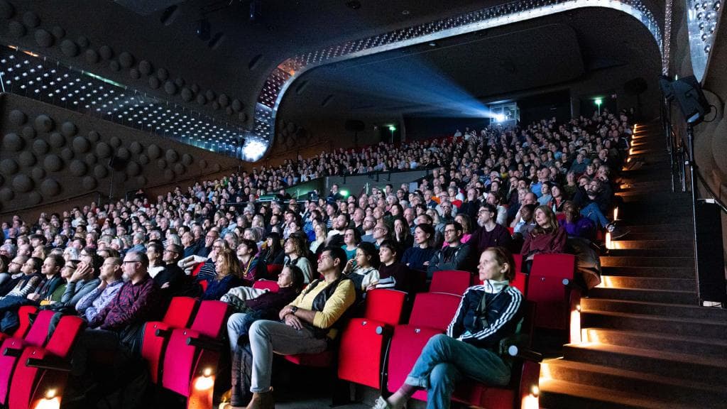 Een bioscoopzaal vol met mensen die een film kijken. 